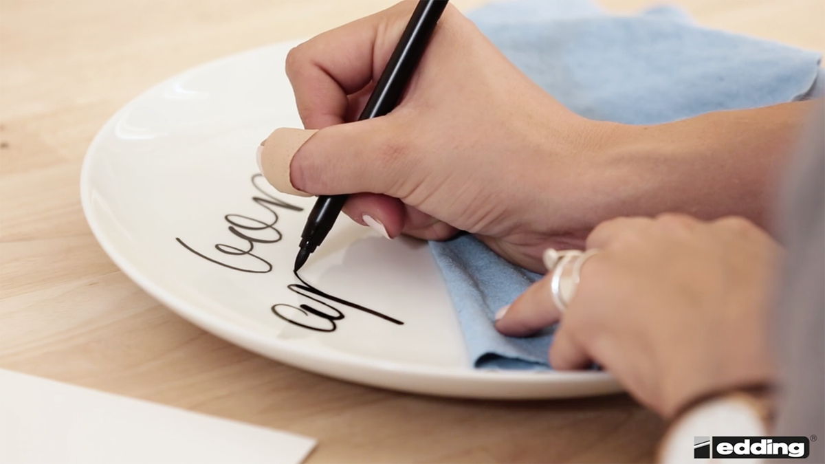 Die Handlettering-Expertin legt ein Mikrofaser-Tuch unter, damit die Schrift nicht versehentlich verwischt.