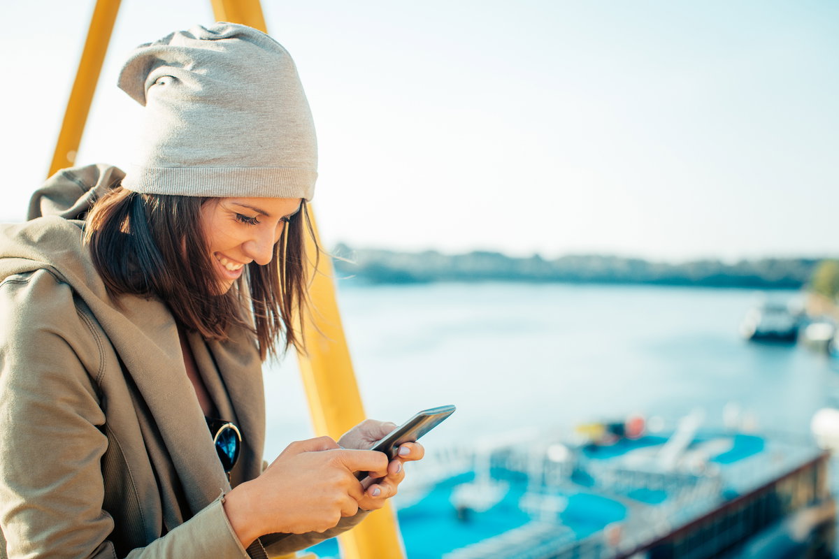 Frau freut sich über eine Nachricht auf ihrem Handy