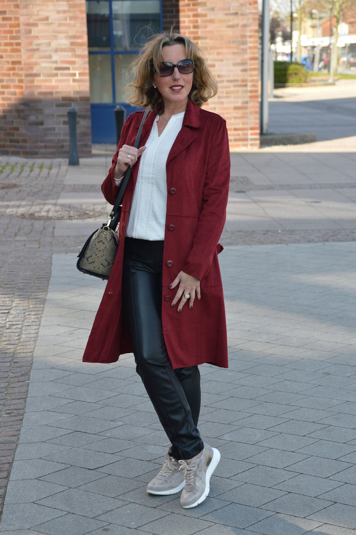 Wow-Look: Sportlich-elegant wird's mit der Kombi aus Lederimitathose zu Sneakern und weißer Bluse. Echter Hingucker: der rote Trench.
