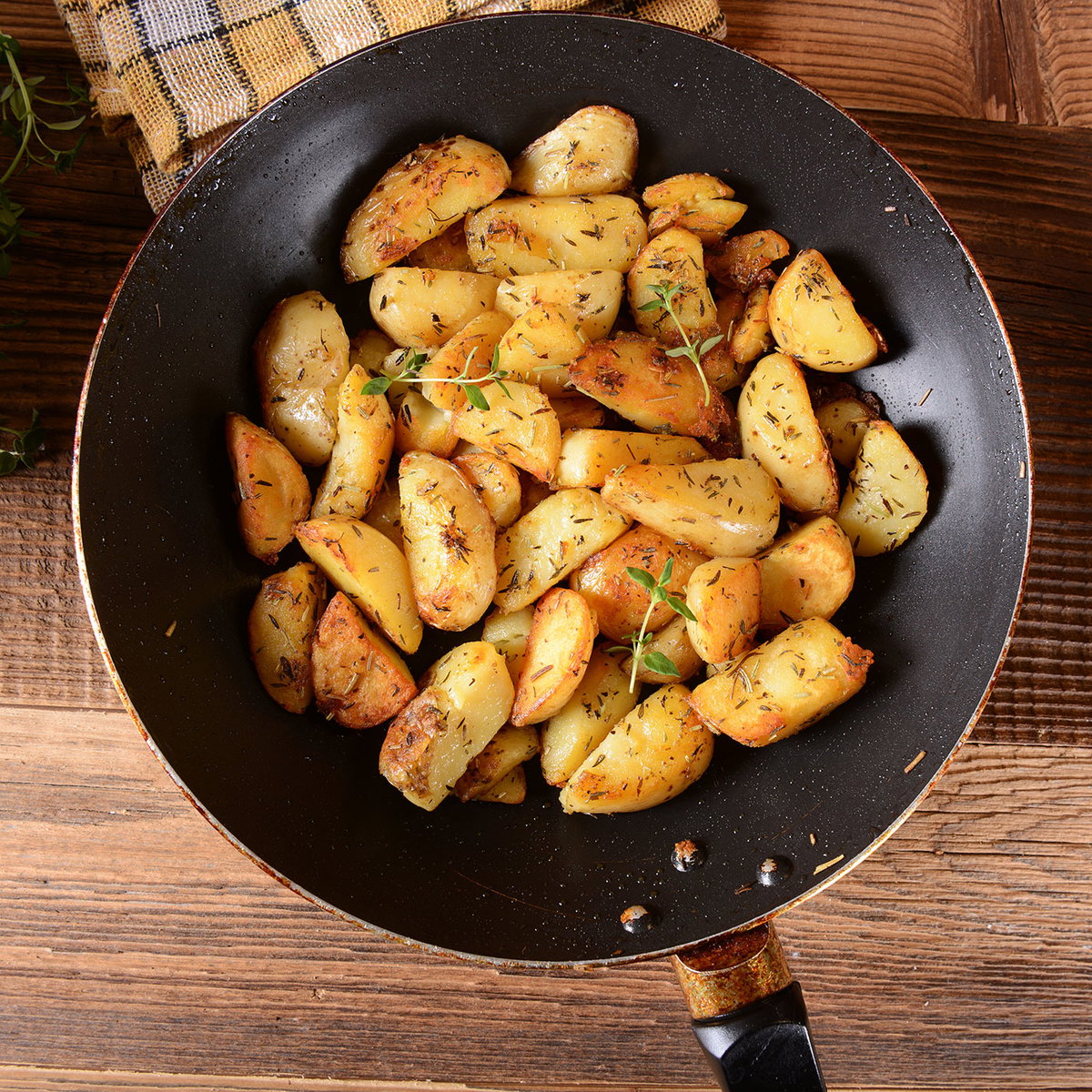 Mit Kräutern gewürzte Bratkartoffeln in einer großen Pfanne