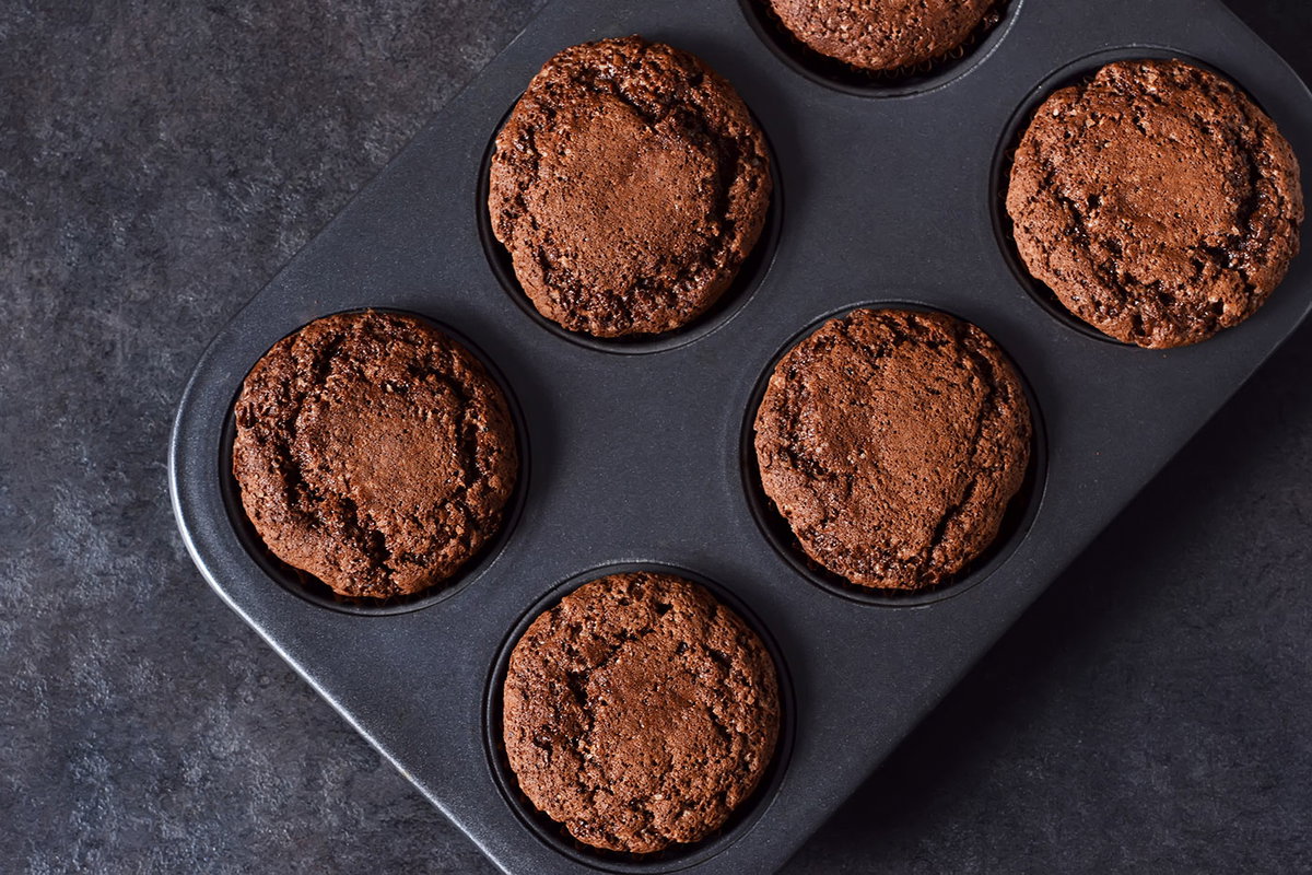 Muffinblech mit Schokoladenmuffins auf dunkler Arbeitsplatte