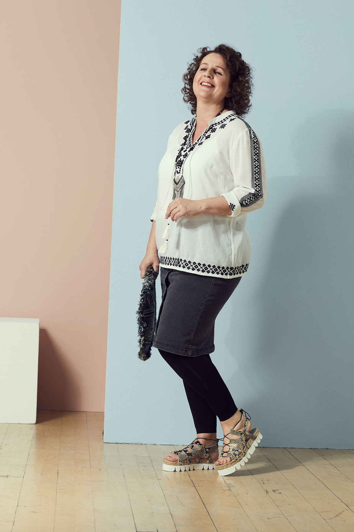 Anja in einer weißen Tunika mit Stickerei zum Jeansrock, Leggings und Turnschuhen