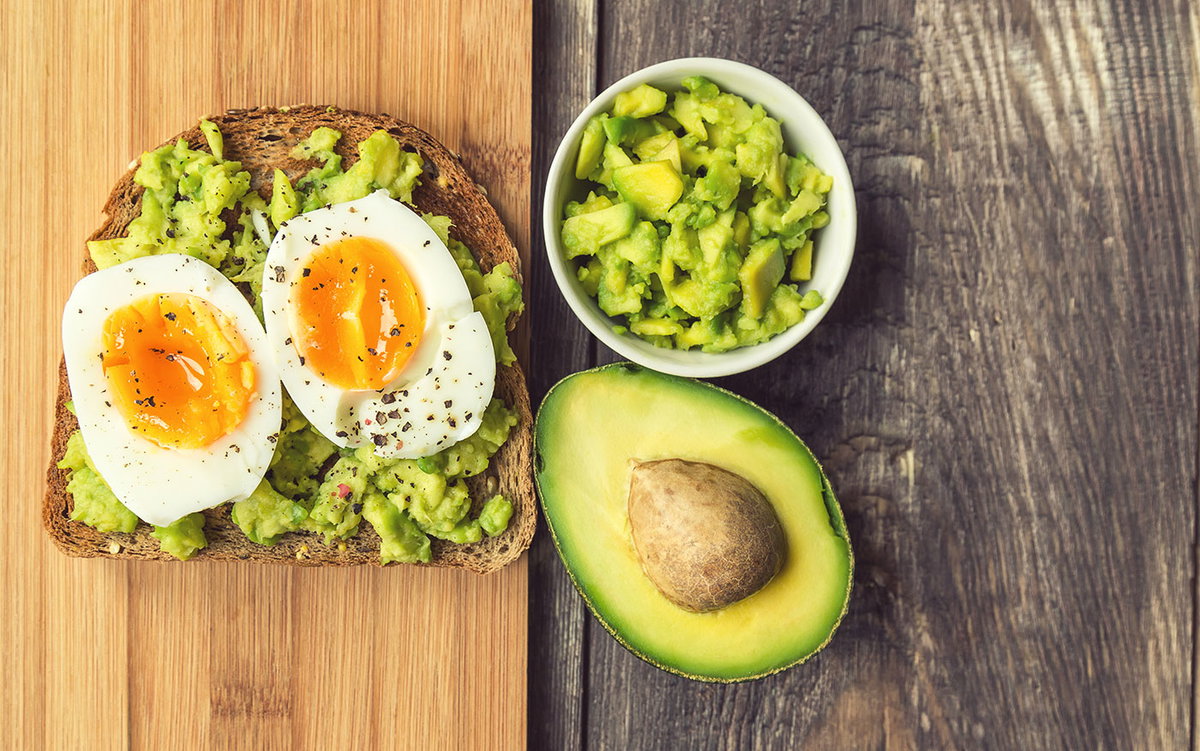 Scheibe Brot mit Avocado und gekochtem Ei auf Holzbrett