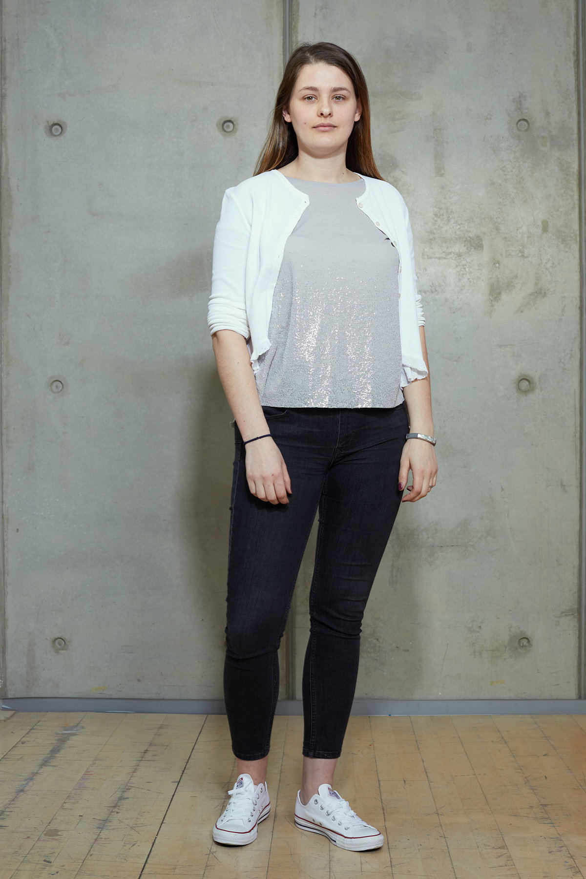 Daniela ungeschminkt in dunkler Jeans und Top zu weißer Strickjacke und Sneakers