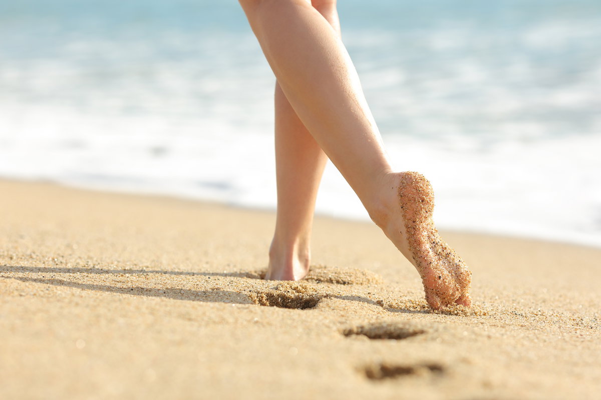 Frauenfüße hinterlassen Spuren am Sandstrand