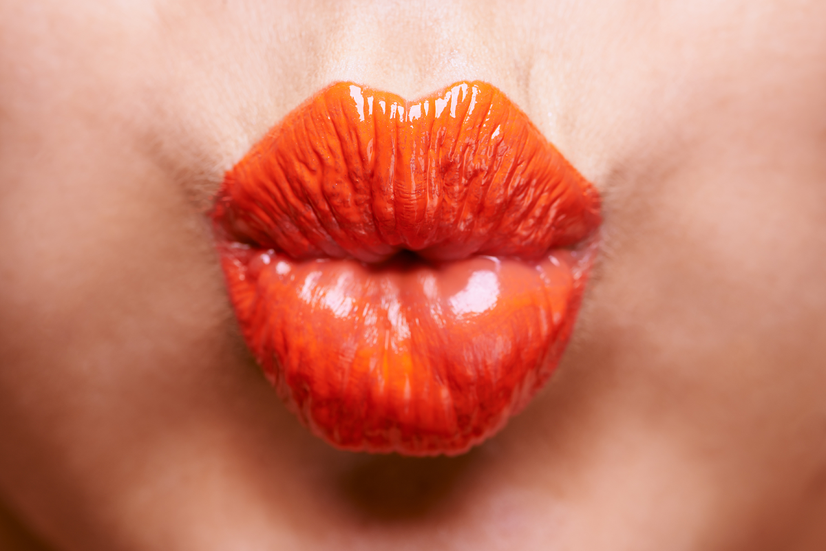 Close-up von gespitzten Lippen mit orangefarbenem Lippenstift